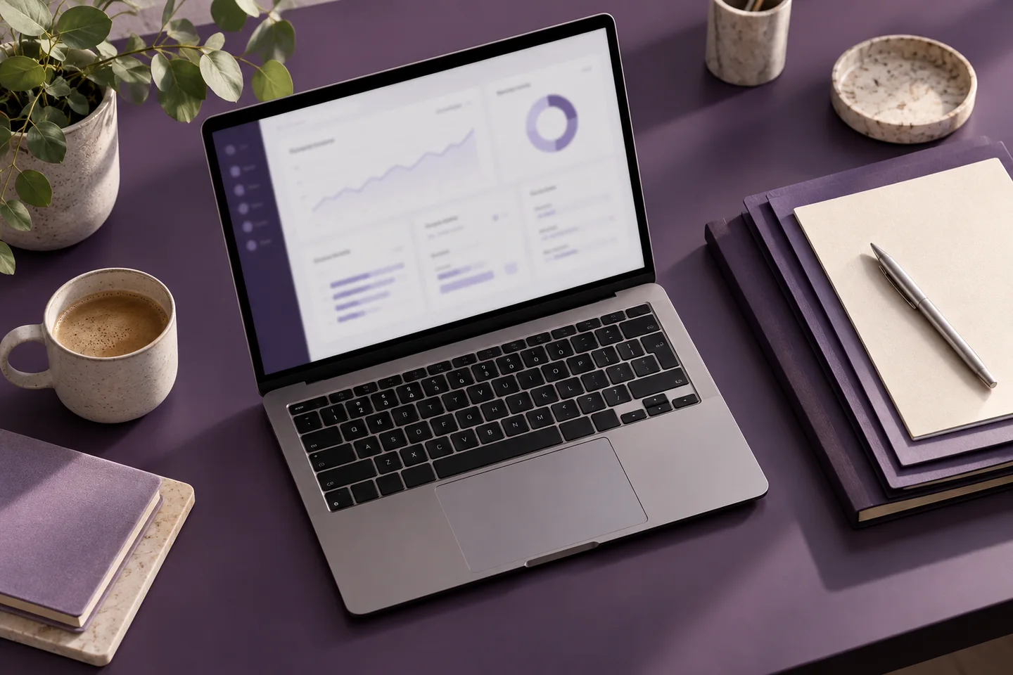 An open laptop on an aubergine desk with a simple blurred non-readable dashboard
